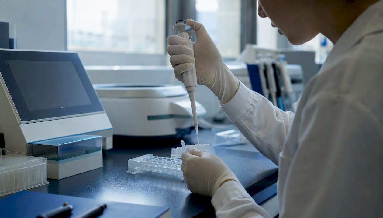 Gloved hands pipetting sample into microtubes