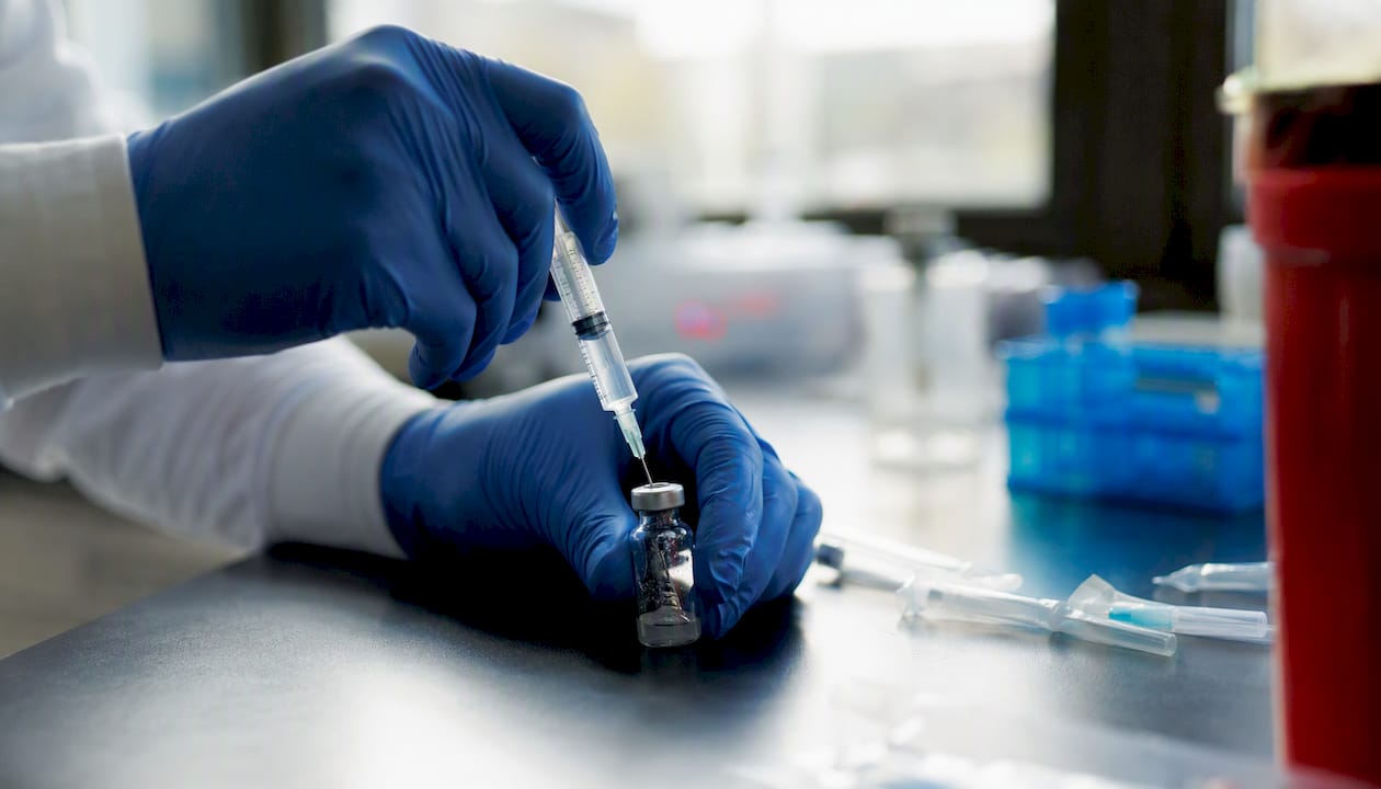 Hands injecting solvent into peptide vial