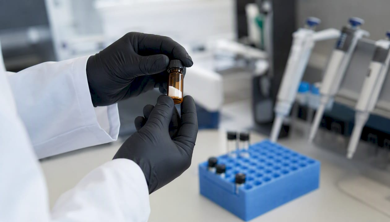 Gloved hands holding vial with lyophilized peptide powder