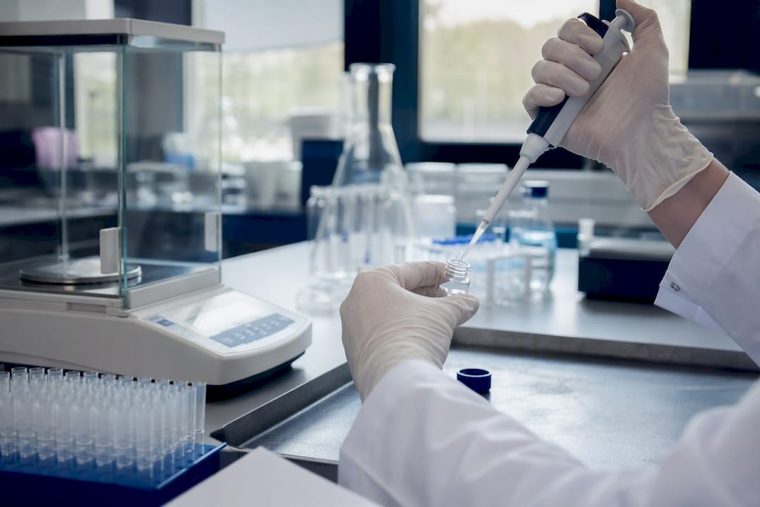 Gloved hand pipetting peptide solution in lab