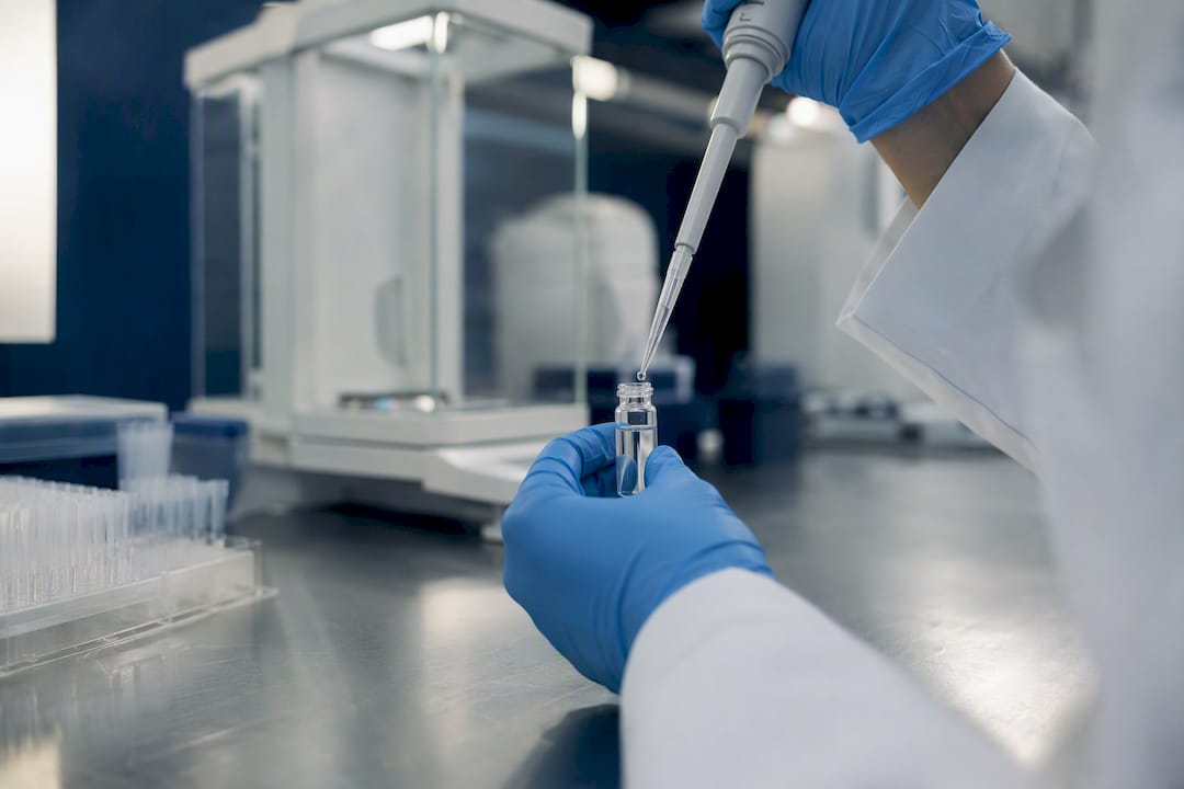 Hands pipetting peptide solution into vial