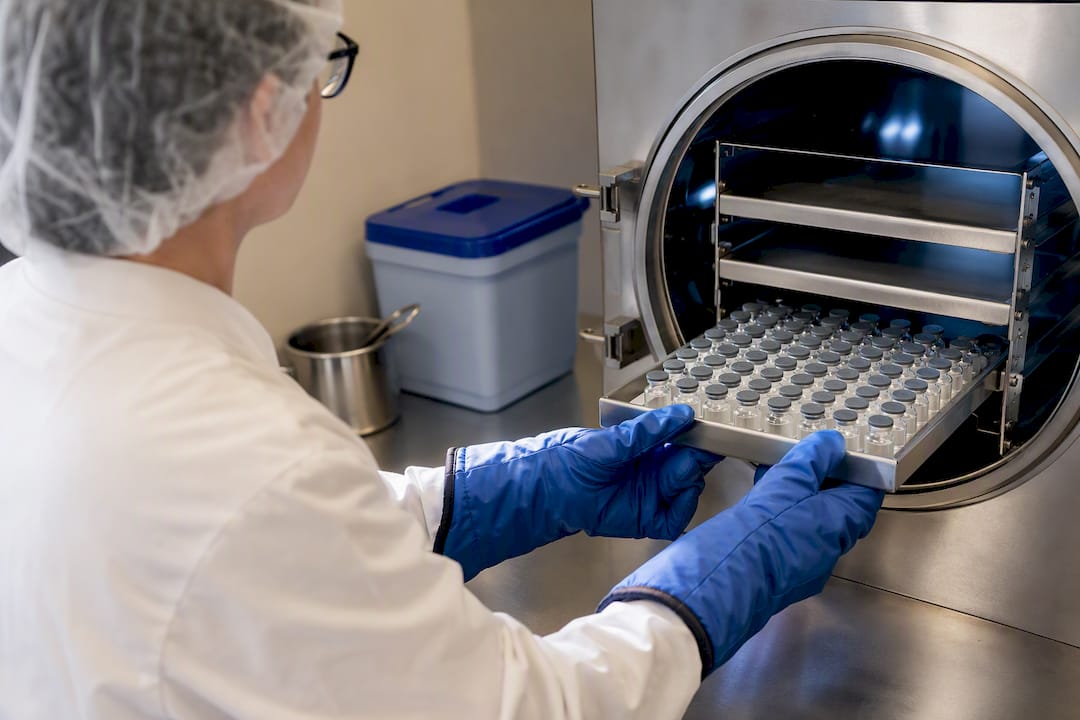 Gloved operator loading a freeze-dryer tray